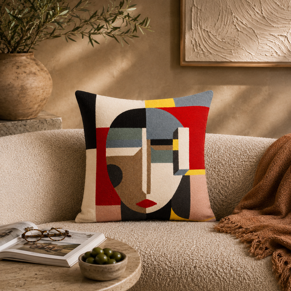 Decorative pillow with abstract design on a beige sofa with a bowl of olives and a book.